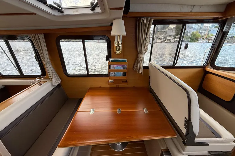 Slide: The Image of Interior of 2014 Ranger Tugs R-27 boat with wooden table and waterfront view. - 49