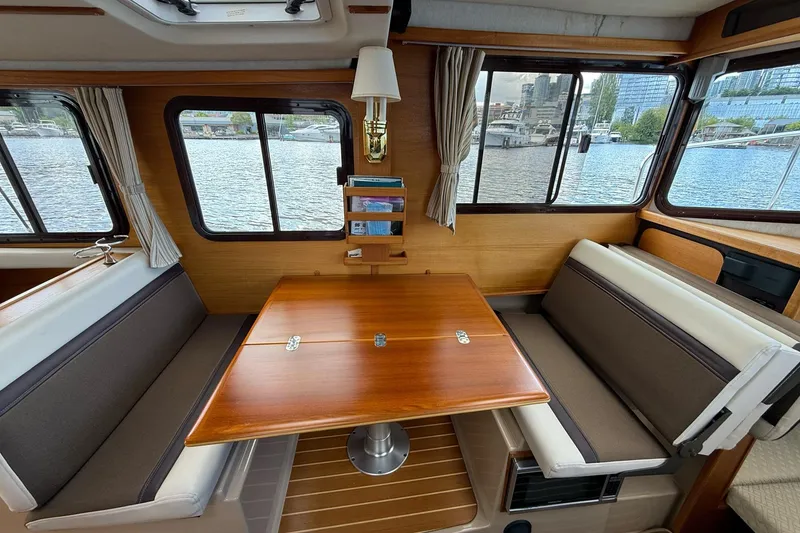 Slide: The Image of Interior of 2014 Ranger Tugs R-27 with wooden table and waterfront view. - 50