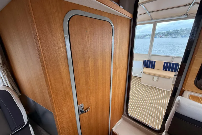 Slide: The Image of Interior view of 2014 Ranger Tugs R-27 boat with wooden door and waterfront seating area. - 54