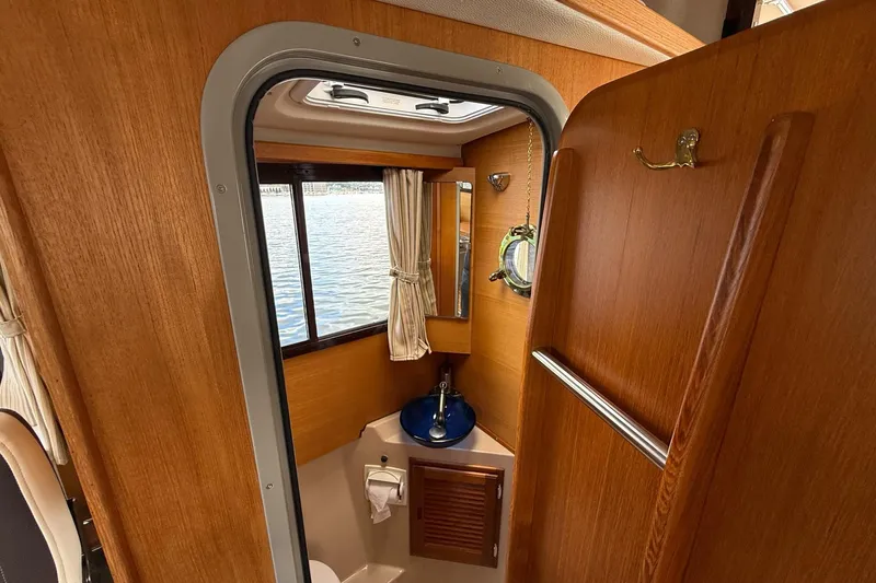 Slide: The Image of Interior of 2014 Ranger Tugs R-27 boat bathroom with wood finish and window view. - 55