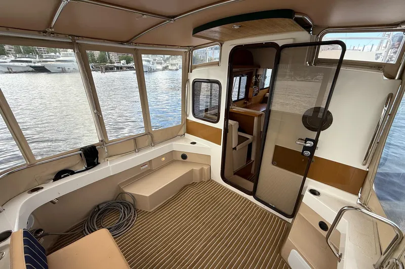 Slide: The Image of 2014 Ranger Tugs R-27 boat interior with spacious seating and waterfront view. - 62