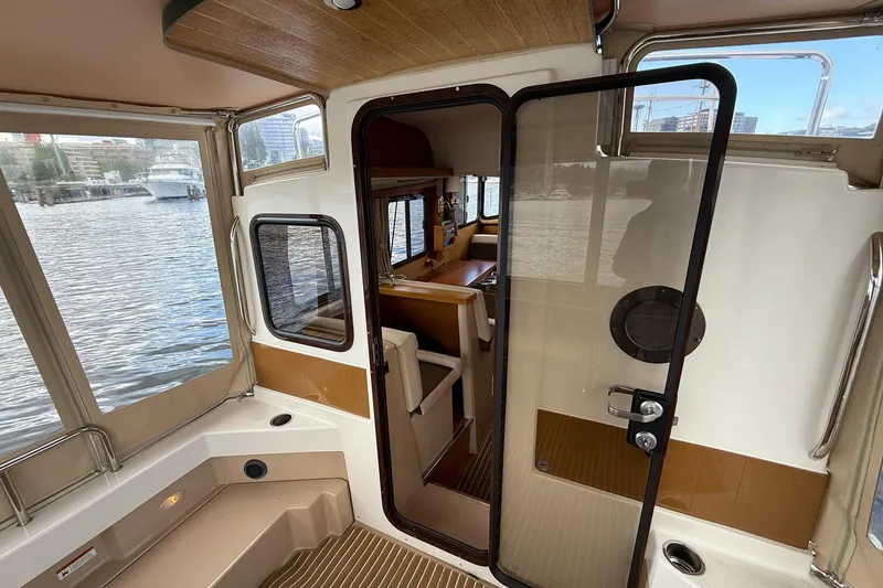 Slide: The Image of 2014 Ranger Tugs R-27 boat interior with open door, overlooking water and cityscape. - 64