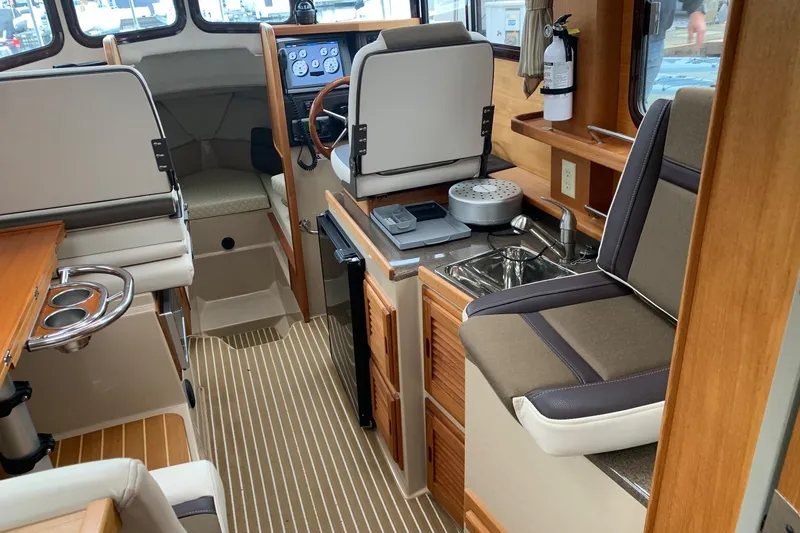 Slide: The Image of Interior of 2014 Ranger Tugs R-27 boat with seating, sink, and navigation controls. - 7