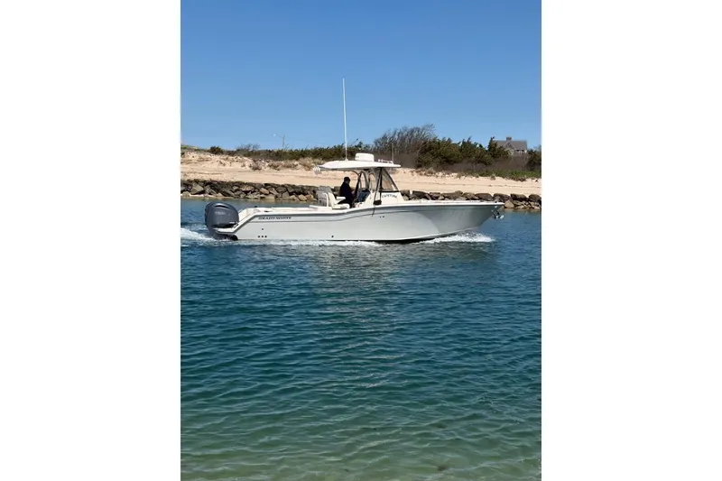 The Image of 2023 Grady-White Canyon 326 boat cruising on clear blue water near a sandy shore. - 1