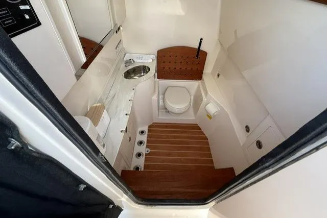 Slide: The Image of 2023 Grady-White Canyon 326 boat interior with compact bathroom and wooden flooring. - 16