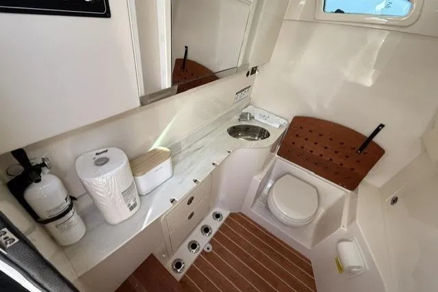 Slide: The Image of 2023 Grady-White Canyon 326 boat bathroom with toilet, sink, and storage. - 17