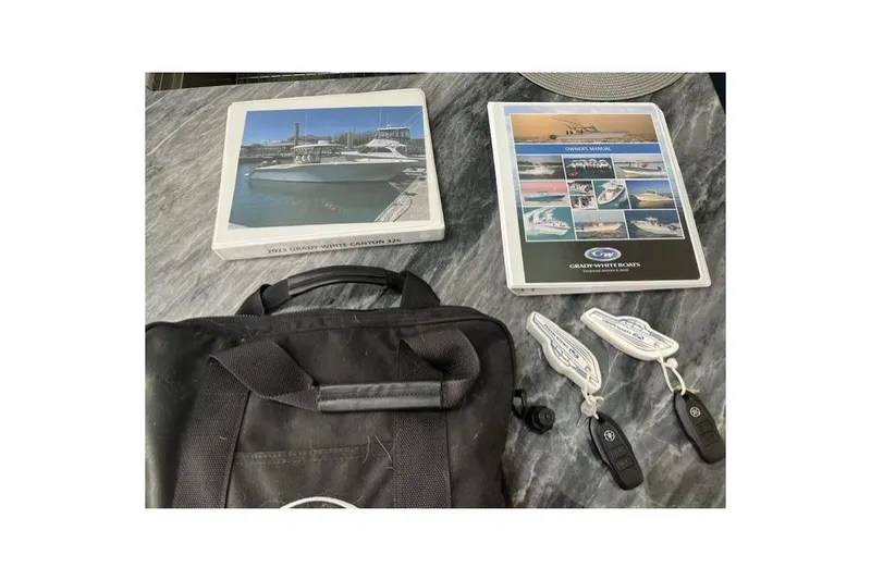 Slide: The Image of 2023 Grady-White Canyon 326 manuals, keys, and bag on a marble surface. - 58