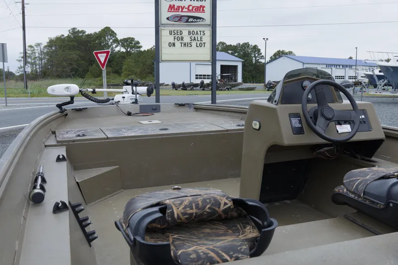 Slide: The Image of 2022 G3 Gator Tough 18 SC boat interior with camo seats, steering console, and outdoor dealership sign. - 10