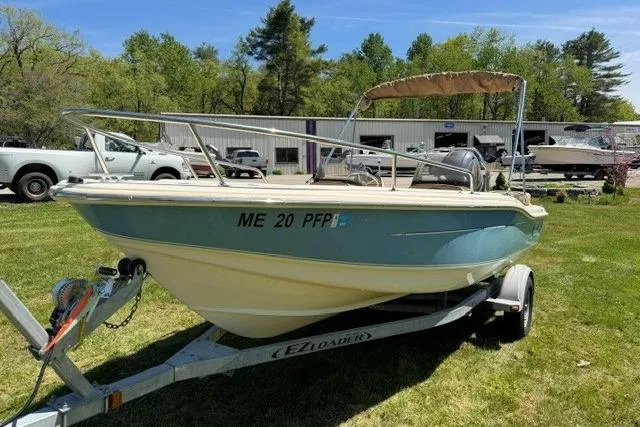 Slide: The Image of 2015 Scout 175 Sport Dorado boat on trailer, parked on grass, with trees and buildings in background. - 2