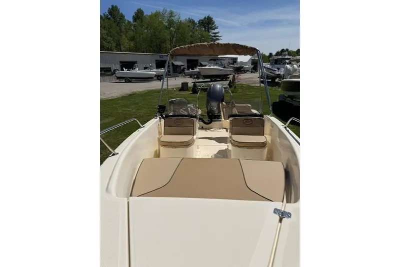 Slide: The Image of 2015 Scout 175 Sport Dorado boat with beige seating and canopy, parked outdoors. - 4