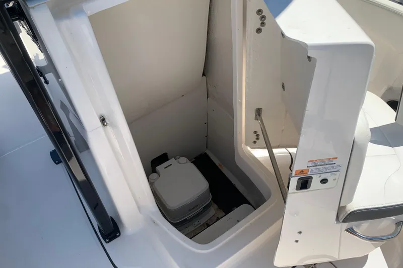 Slide: The Image of 2023 Robalo R222 Center Console boat interior with compact marine toilet. - 6