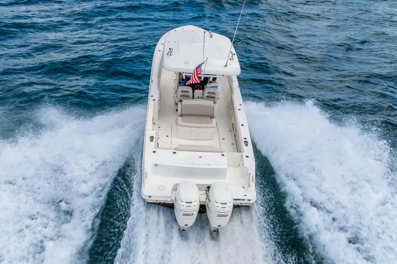 Slide: The Image of 2017 Boston Whaler 330 Outrage cruising on open water, rear view with twin engines. - 14