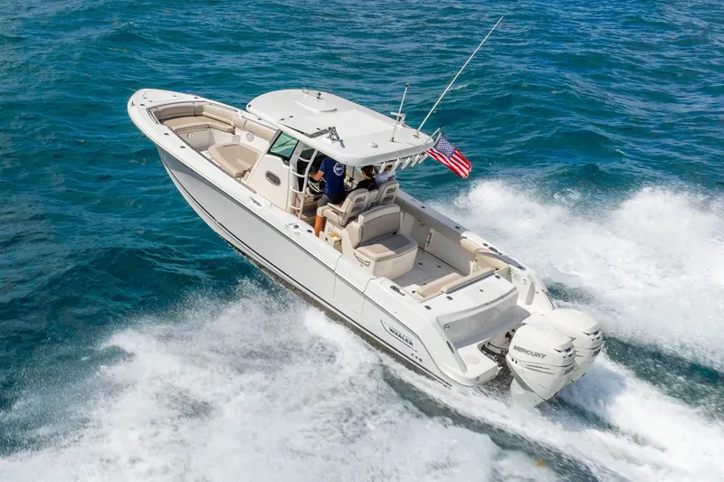 Slide: The Image of 2017 Boston Whaler 330 Outrage cruising on open water with American flag. - 2