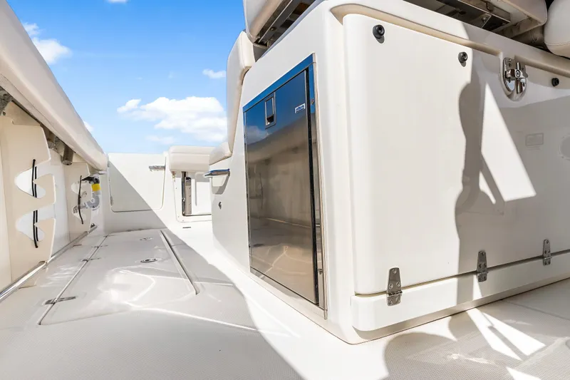 Slide: The Image of 2017 Boston Whaler 330 Outrage deck, featuring sleek storage and seating under a clear blue sky. - 24