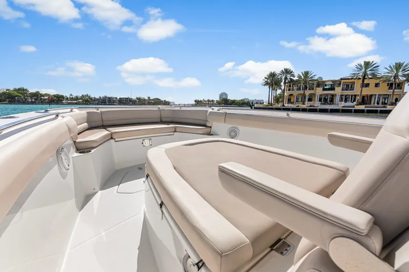 Slide: The Image of 2017 Boston Whaler 330 Outrage boat interior with beige seating, scenic waterfront view. - 25