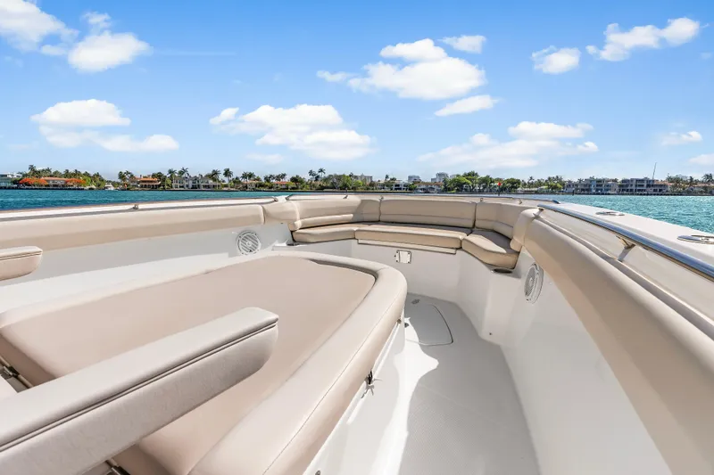 Slide: The Image of 2017 Boston Whaler 330 Outrage boat interior with beige seating, ocean view, and blue sky. - 26