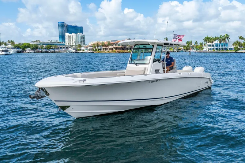 Slide: The Image of 2017 Boston Whaler 330 Outrage boat cruising on a sunny day with cityscape background. - 3