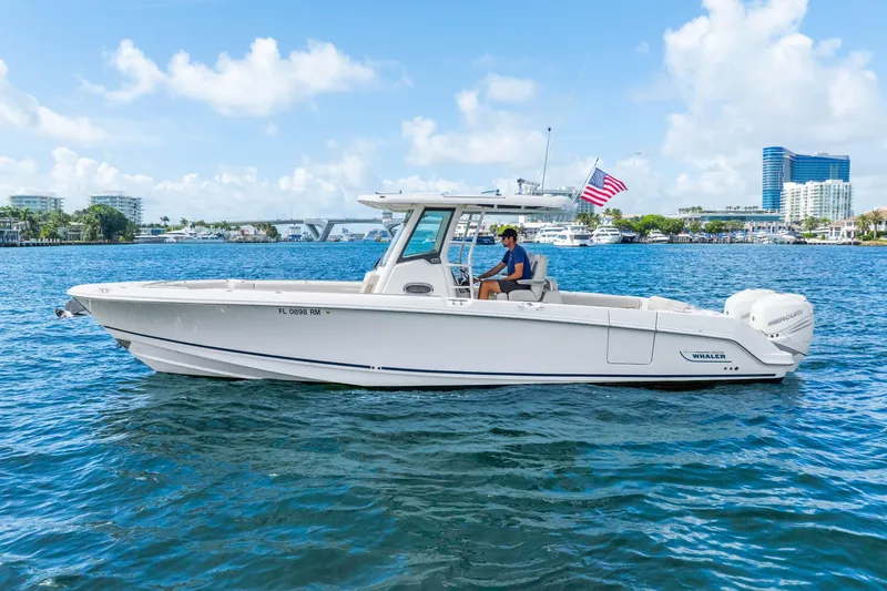 Slide: The Image of 2017 Boston Whaler 330 Outrage boat cruising on a sunny day with cityscape background. - 4