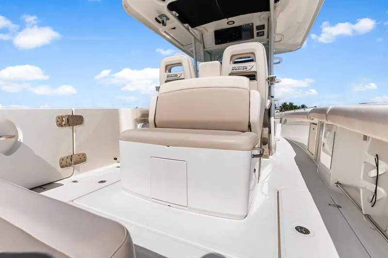 Slide: The Image of 2017 Boston Whaler 330 Outrage boat interior with beige seating under a clear blue sky. - 42