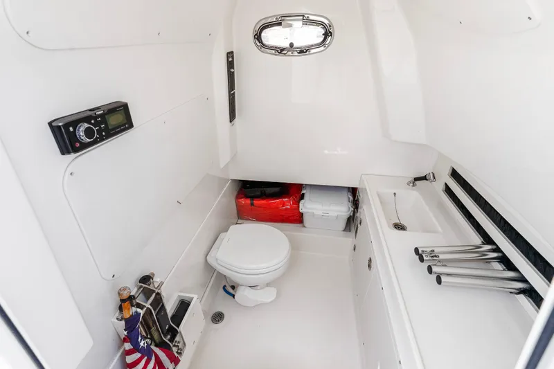 Slide: The Image of 2017 Boston Whaler 330 Outrage cabin interior with toilet, sink, and storage. - 46
