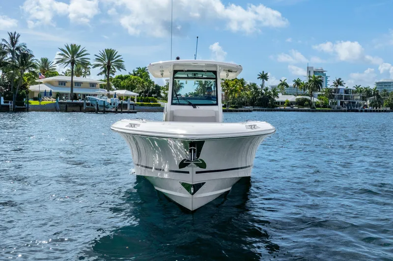 Slide: The Image of 2017 Boston Whaler 330 Outrage boat on water, with palm trees and houses in the background. - 5