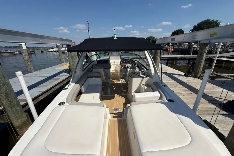 Slide: The Image of 2011 Sea Ray 270 SLX boat docked, featuring spacious seating and a black canopy. - 10