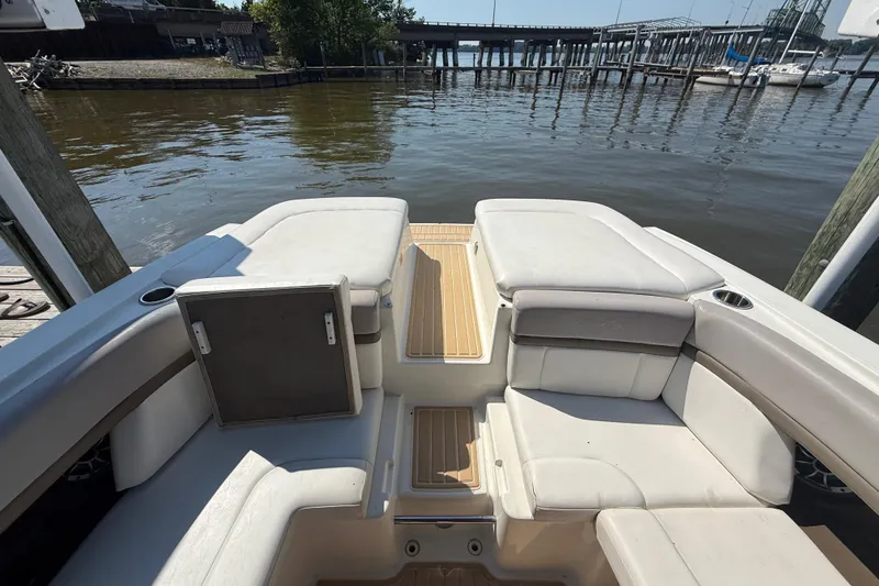 Slide: The Image of 2011 Sea Ray 270 SLX boat interior with white seating, docked by a calm waterfront. - 11