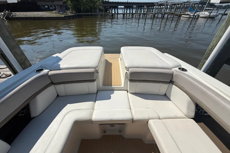 Slide: The Image of 2011 Sea Ray 270 SLX boat interior with white seating, docked by the water. - 12