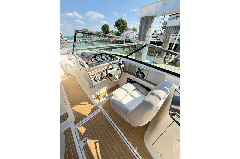 Slide: The Image of 2011 Sea Ray 270 SLX boat cockpit with steering wheel and dashboard, docked at marina. - 32