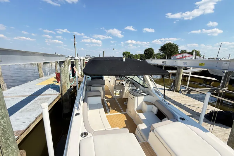 Slide: The Image of 2011 Sea Ray 270 SLX boat docked, featuring spacious seating and a black canopy. - 48