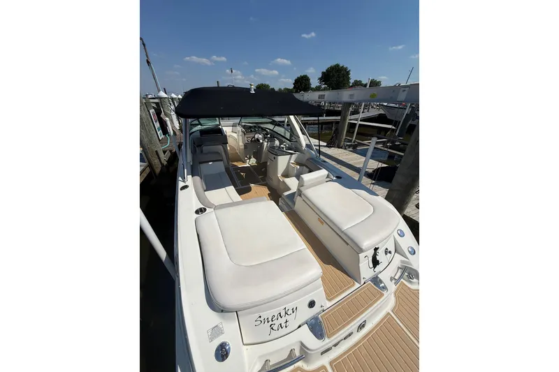 Slide: The Image of 2011 Sea Ray 270 SLX boat with white seating and black canopy at dock. - 9