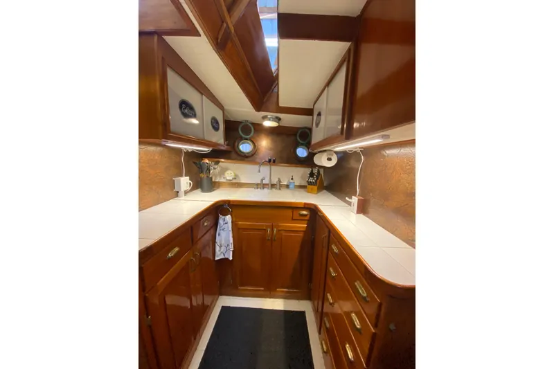 Slide: The Image of 1939 Elco Motor Yacht kitchen with wooden cabinets and porthole windows. - 17