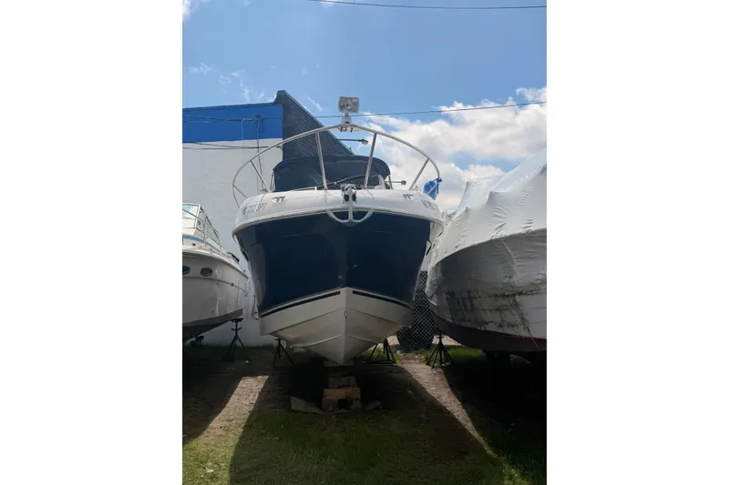 Slide: The Image of 2004 Four Winns 268 Vista boat on land, surrounded by other boats, under a blue sky. - 1