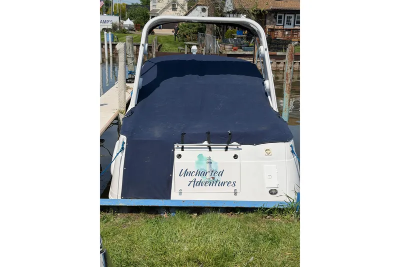 Slide: The Image of 2004 Four Winns 268 Vista boat named "Uncharted Adventures" docked at a marina. - 2