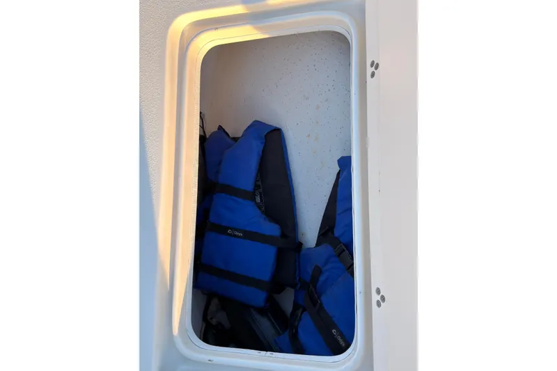 Slide: The Image of Storage compartment with blue life jackets on a 2013 Carolina Skiff 198 DLV boat. - 27