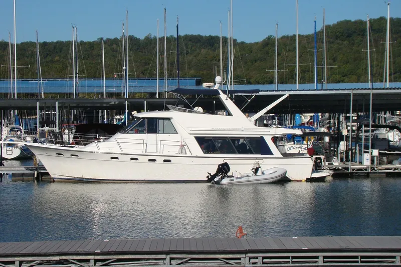 The Image of 2001 Bayliner 4788 Pilot House Motoryacht docked at marina with inflatable boat. - 0
