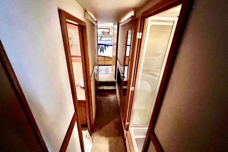 Slide: The Image of Narrow hallway inside 2001 Bayliner 4788 Pilot House Motoryacht, featuring wooden doors and carpeted floor. - 17