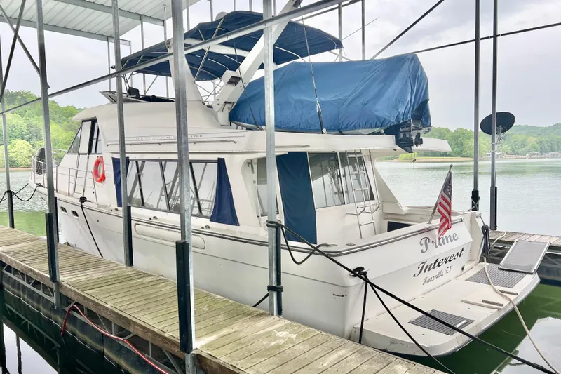 Slide: The Image of 2001 Bayliner 4788 Pilot House Motoryacht docked, covered with blue tarp, American flag displayed. - 2