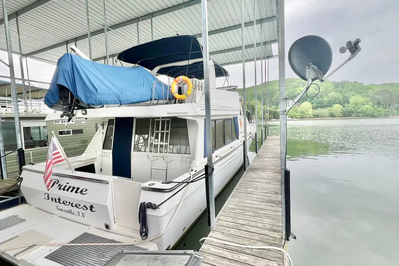 Slide: The Image of 2001 Bayliner 4788 Pilot House Motoryacht docked, covered with blue tarp, near serene lake. - 3