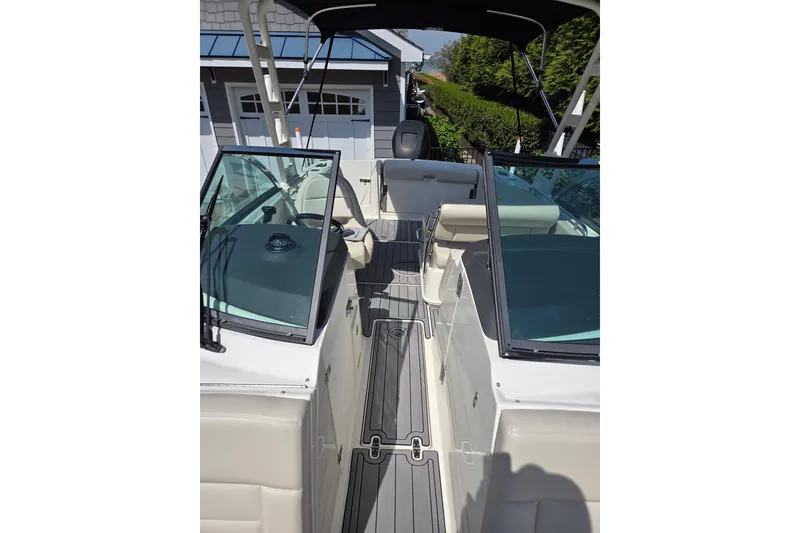 Slide: The Image of 2018 Boston Whaler 230 Vantage boat interior with seating and windshield, docked near a house. - 18