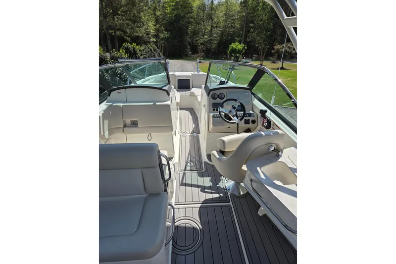 Slide: The Image of 2018 Boston Whaler 230 Vantage boat interior with steering wheel and seating, surrounded by lush greenery. - 2