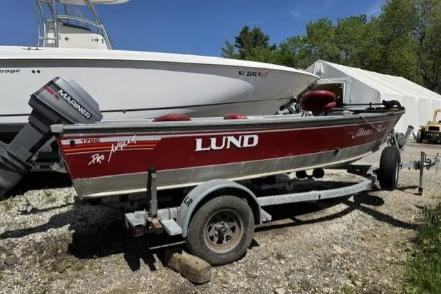 The Image of 1993 Lund 1700 Pro Angler boat on trailer, red and silver, parked outdoors. - 1