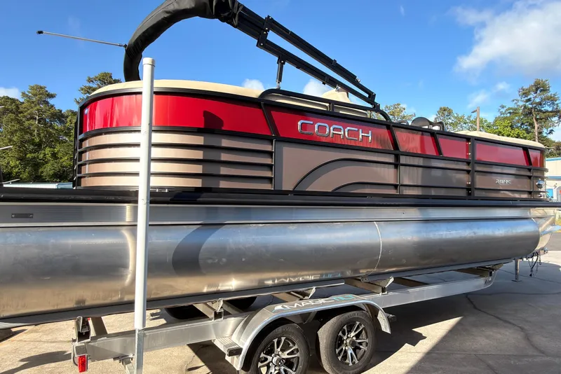 The Image of 2026 Coach Pontoons 243 RFC pontoon boat on trailer, featuring sleek red and silver design. - 0
