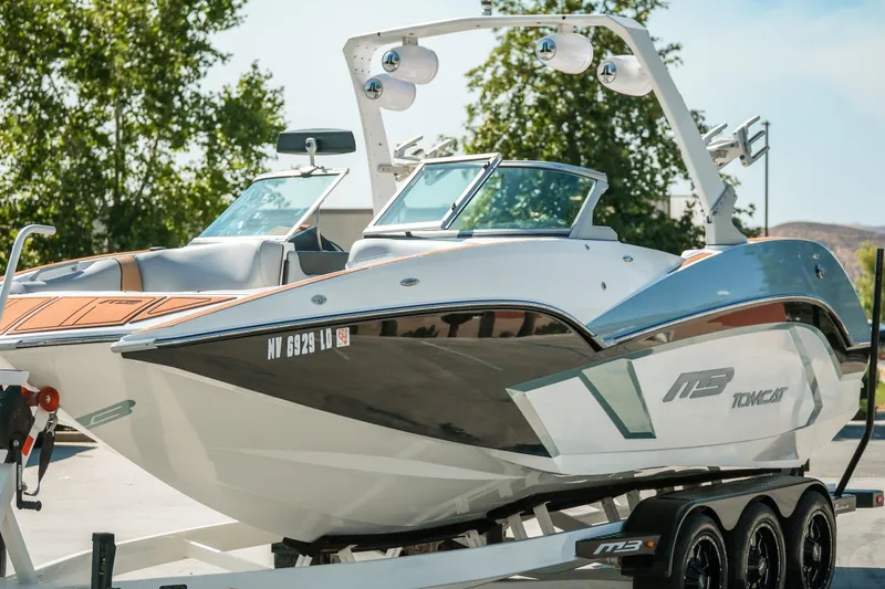 Slide: The Image of 2021 MB F24 Tomcat boat on trailer, parked outdoors with trees in background. - 7