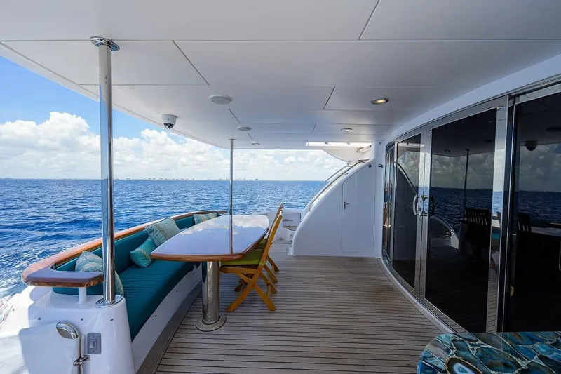 Slide: The Image of Luxurious 2007 Hatteras 80 Motor Yacht deck with ocean view, featuring elegant seating and dining area. - 10