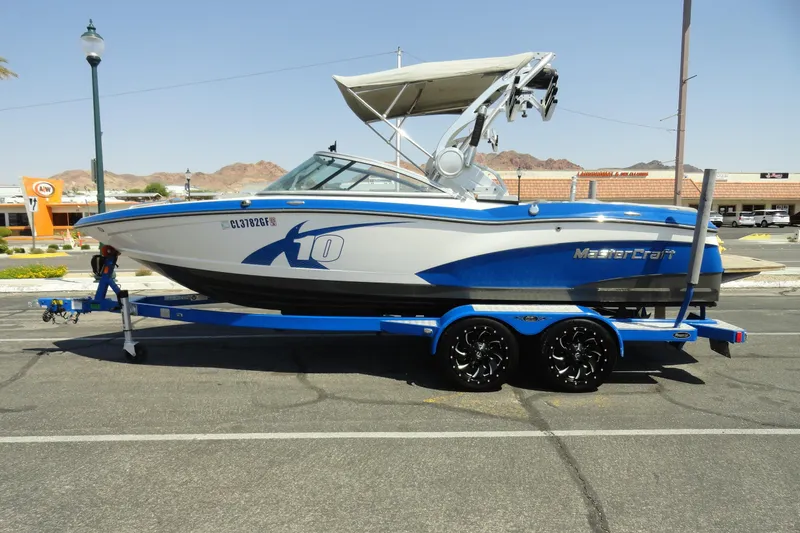 The Image of 2013 MasterCraft X-10 boat on trailer, parked in sunny outdoor setting. - 1