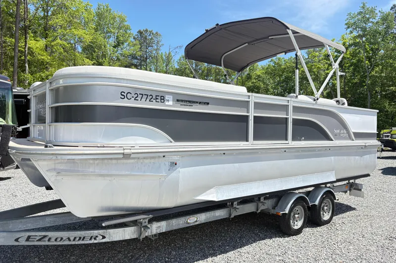 The Image of 2022 SunCatcher Select 22RF pontoon boat on EZ Loader trailer, parked outdoors. - 2