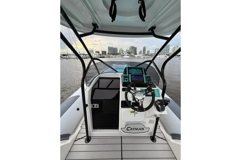 Slide: The Image of 2024 Ranieri Cayman 27.0 Sport boat cockpit with modern controls and city skyline view. - 16