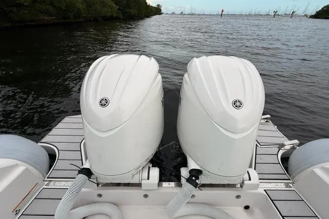 Slide: The Image of 2024 Ranieri Cayman 27.0 Sport with dual outboard motors on a calm waterway. - 21