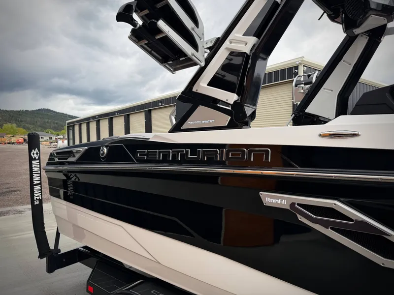 Slide: The Image of 2023 Centurion Ri230 boat, black and white, parked outdoors. - 15
